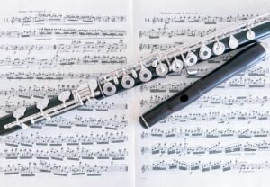 Close-up of a flute resting on sheet music pages, emphasizing musical composition.